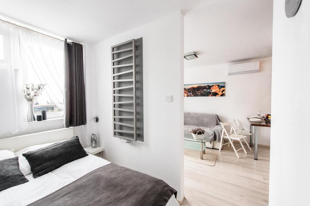 een slaapkamer met een bed en een woonkamer met een tafel bij Alma Apartments Grzybowska in Warschau