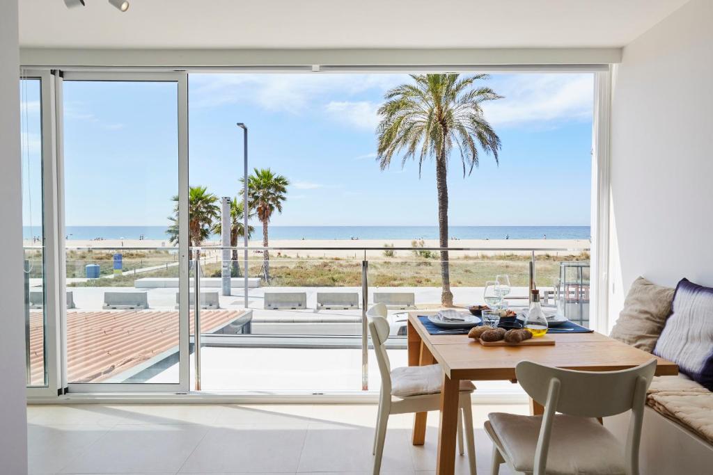 a dining room with a table and a view of the beach at Sunny Beachfront Escape in Castelldefels