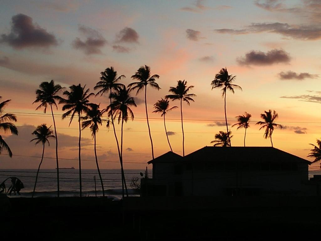 a group of palm trees in front of a sunset at Ocean on house in Unawatuna
