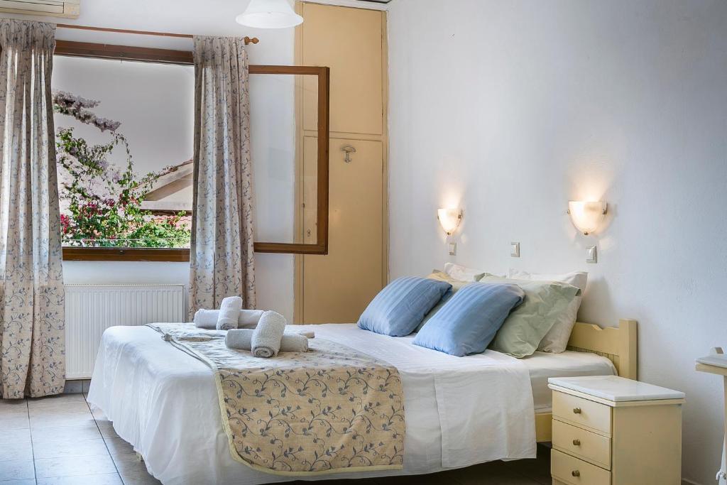sypialnia z łóżkiem z niebieskimi poduszkami i oknem w obiekcie Argostoli Rooms w mieście Argostoli
