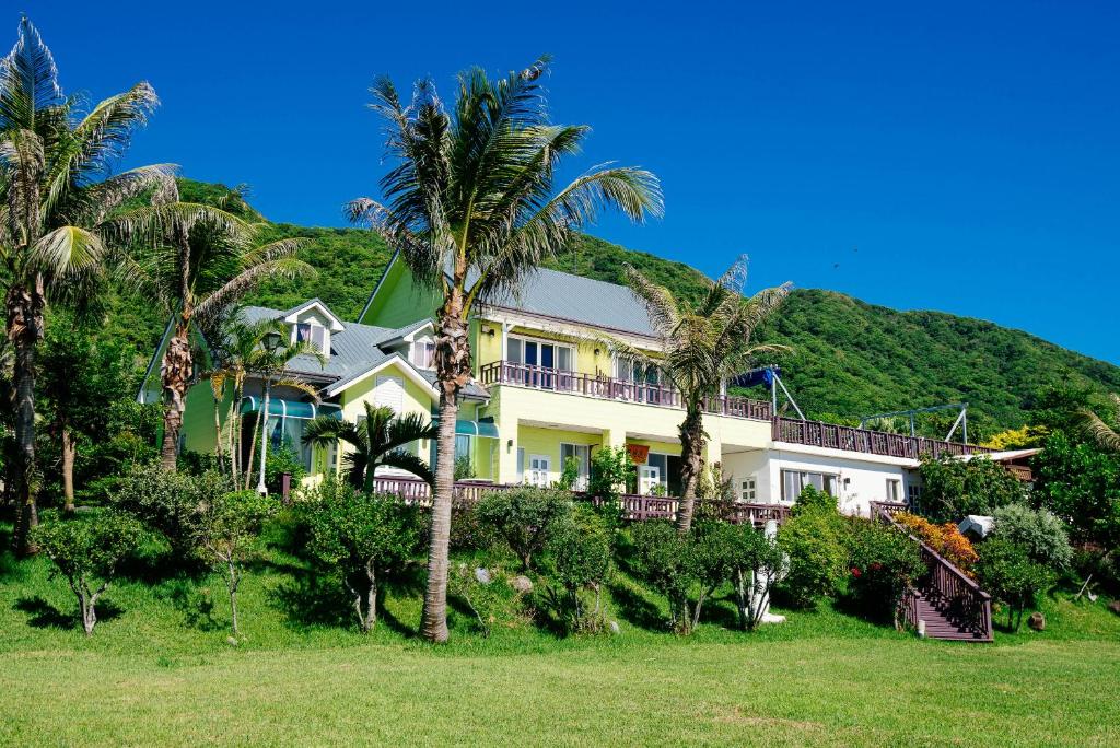 dom z palmami przed wzgórzem w obiekcie Sea-Hi B&B w mieście Yanliau