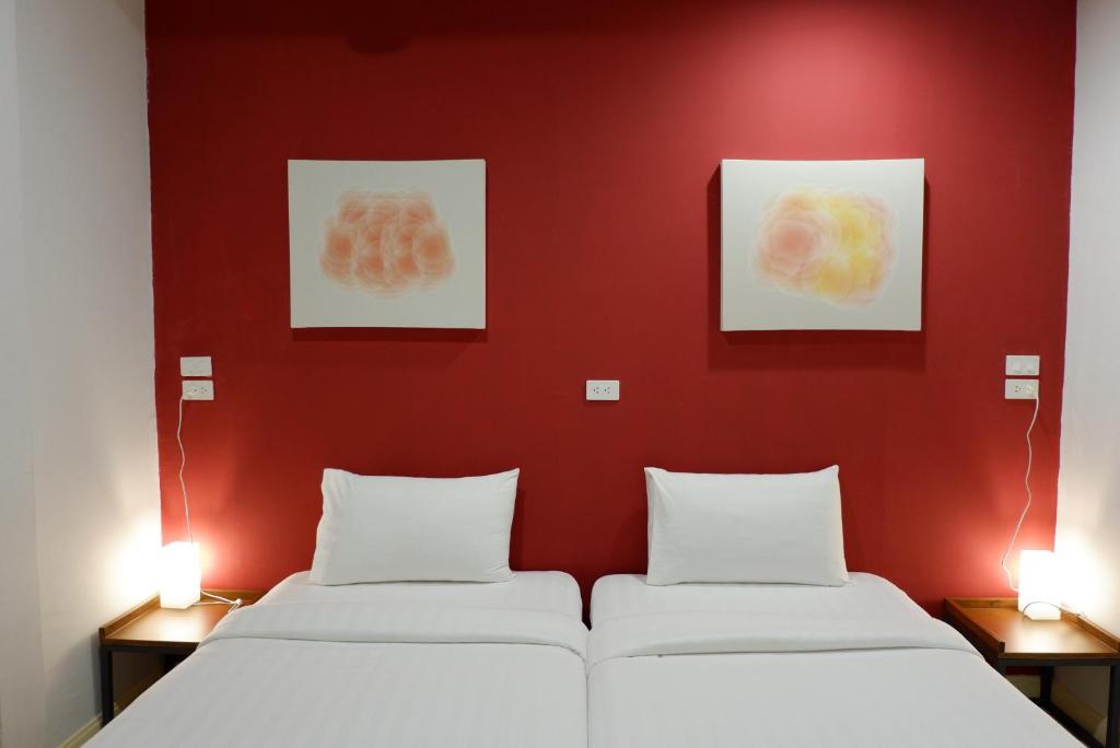 two beds in a room with red walls and pictures at Peace Factory Hostel in Bangkok