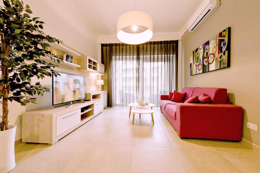 Una sala de estar con un sofá rojo y un televisor. en Luxury Apartment with Pool, en Sliema
