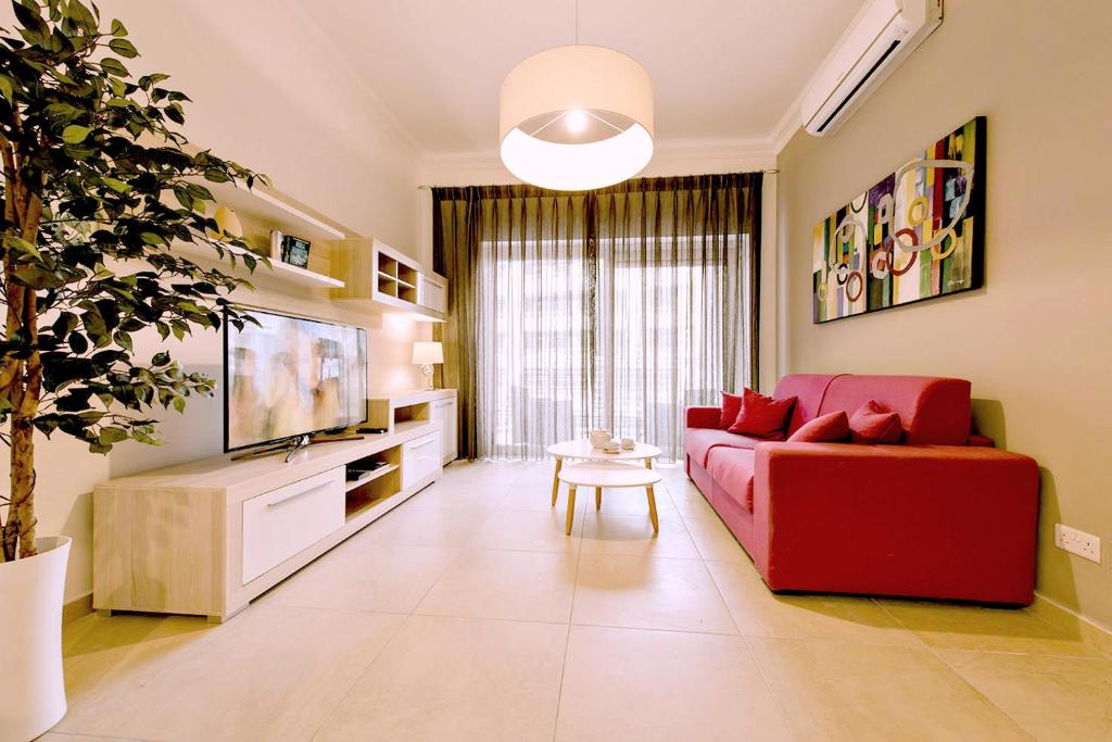 a living room with a red couch and a tv at Luxury Apartment with Pool in Sliema