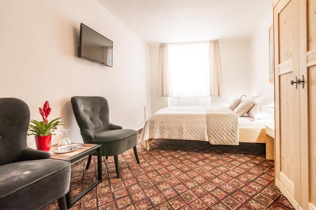 捷克克魯姆洛夫的住宿－家庭旅館，一间卧室配有一张床、两把椅子和一张桌子