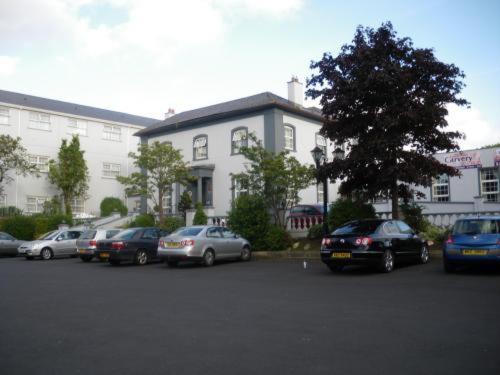 un parcheggio con auto parcheggiate di fronte a un edificio di Drummond Hotel a Ballykelly