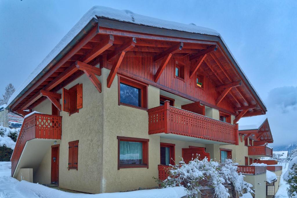 un bâtiment avec des balcons rouges dans la neige dans l'établissement Chalet Etoiles - Les Chalets des Etoiles, à Chamonix-Mont-Blanc