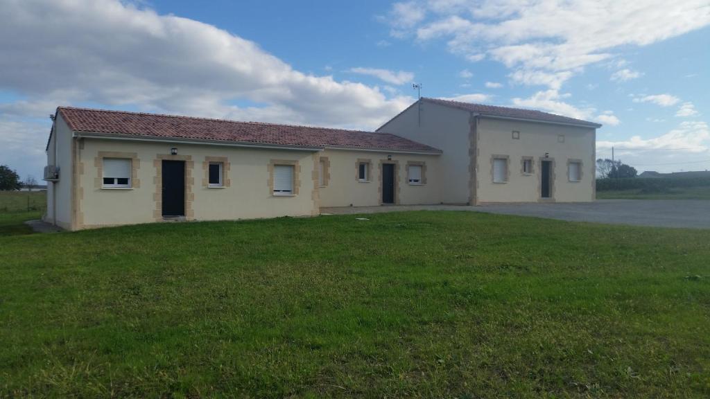 un edificio blanco con un campo de hierba delante de él en La clé des champs en Clam