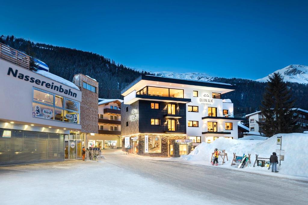 a large building with people standing in the snow at Biwak Appartements in Sankt Anton am Arlberg