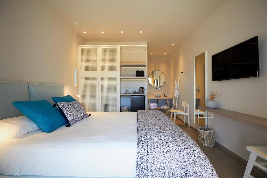 a bedroom with a large white bed with blue pillows at Vigla Hotel in Aegiali