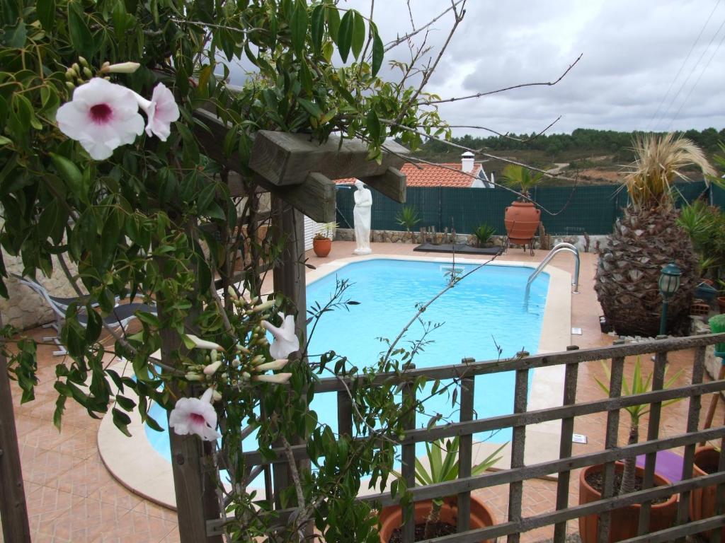 a swimming pool in a yard with a fence and flowers at Casa Helena in Aljezur