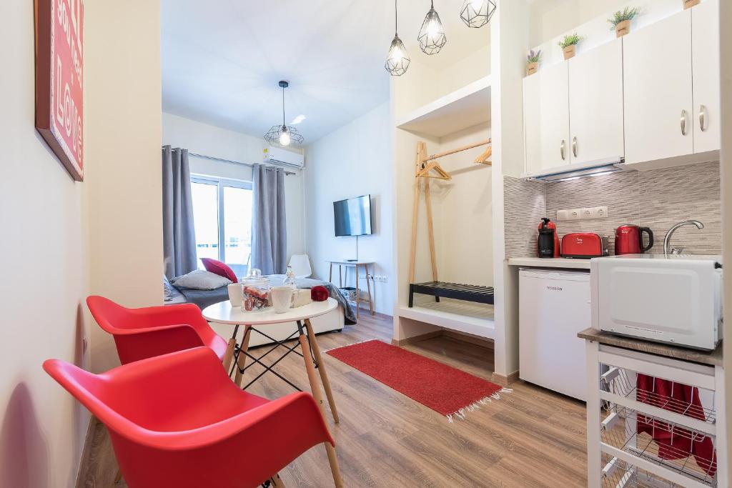 uma cozinha e sala de estar com cadeiras vermelhas e uma mesa em Athenz Downtown Studio em Atenas
