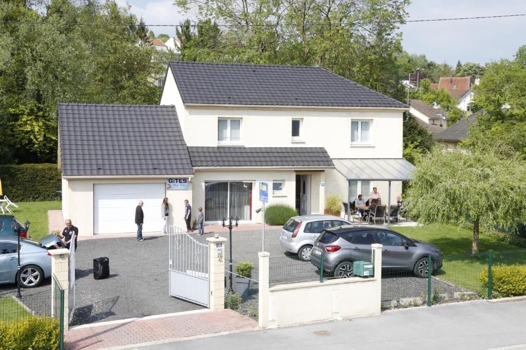 a white house with cars parked in a parking lot at Gîtes Ciel Bleu in Rethel