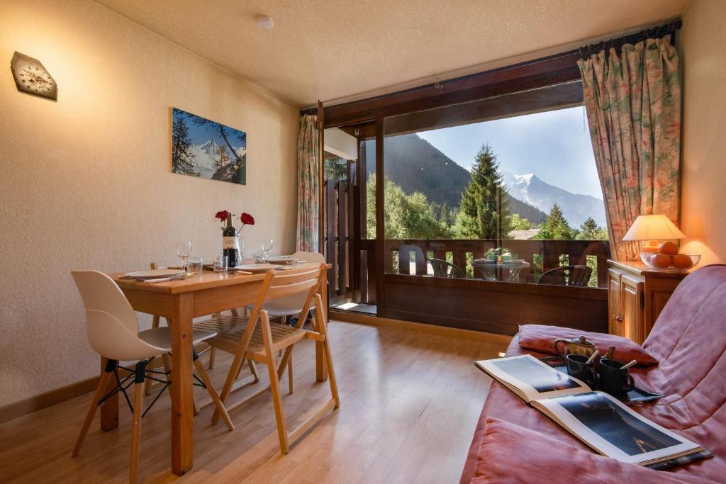 a living room with a table and a large window at Résidence La Verte 15 ski in ski out - Happy Rentals in Chamonix