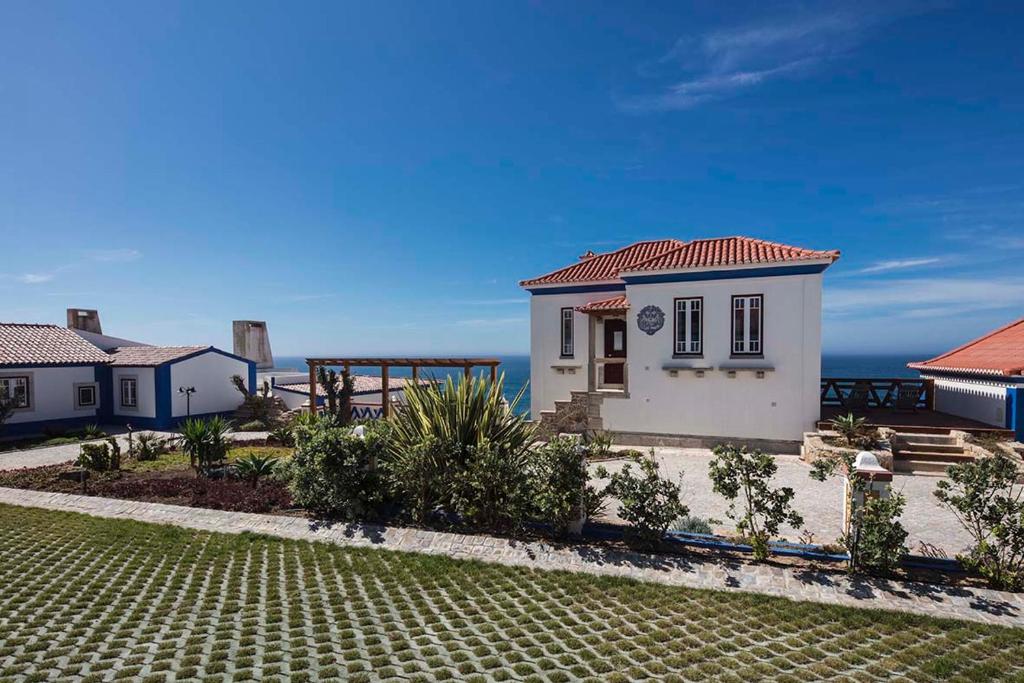 a small white house with the ocean in the background at Chalet O Amorzinho Sintra Praia in Sintra