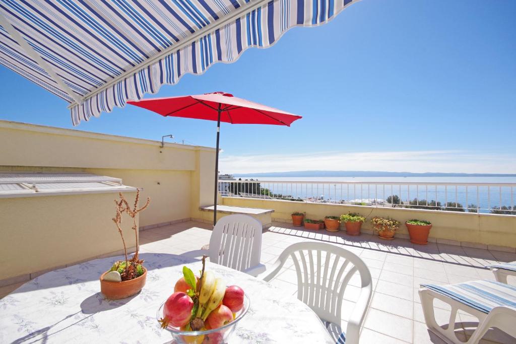 un tavolo con ombrellone rosso su un balcone di Apartments Kus a Spalato (Split)