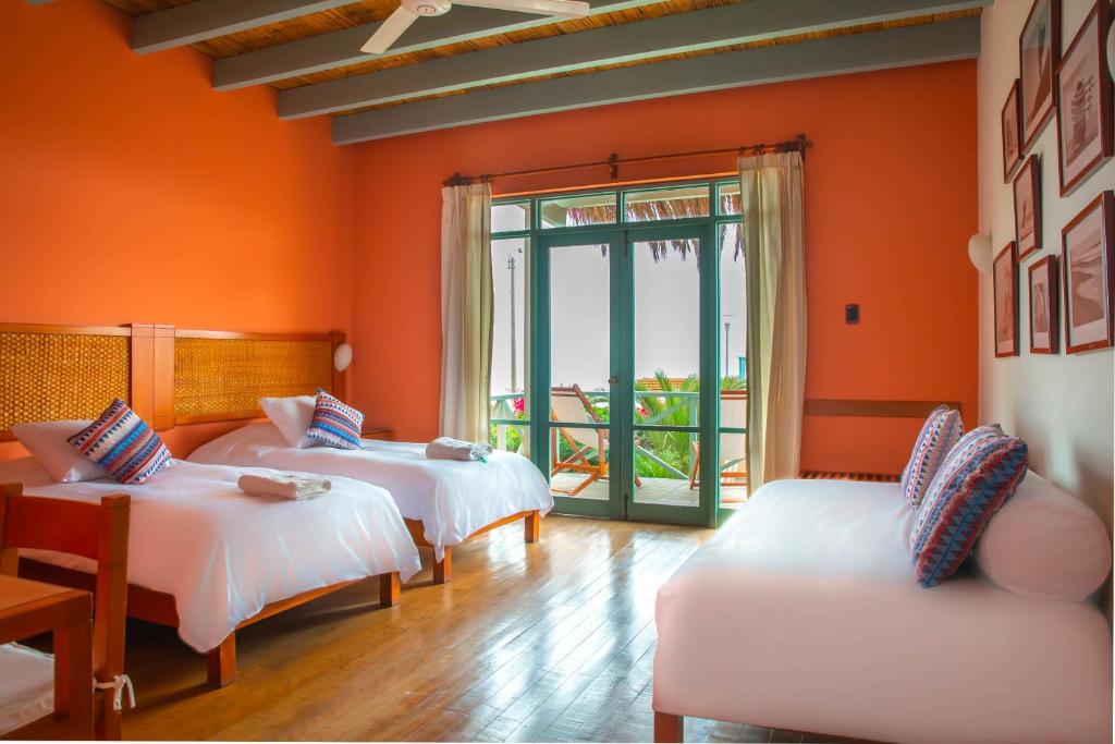 2 camas en una habitación con paredes de color naranja en Chicama Boutique Hotel & Spa, en Puerto Chicama