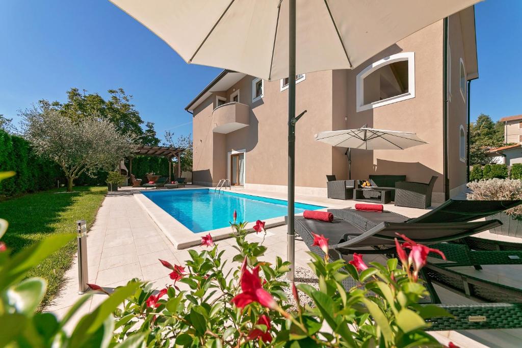 a villa with a swimming pool and two chairs and an umbrella at Villa Dani in Vižinada