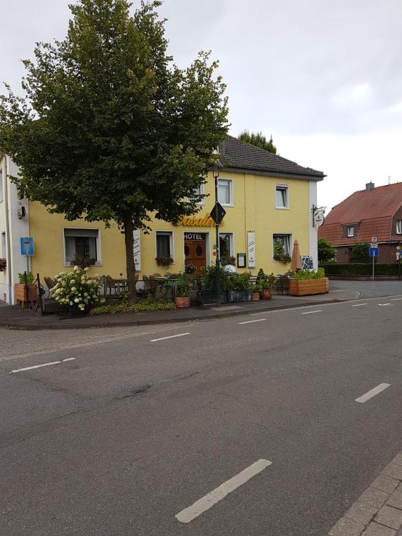 a yellow house with a tree on the side of a street at Casalino in Wachtendonk