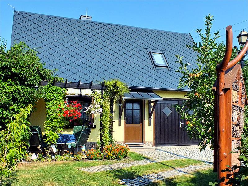 une maison avec une terrasse couverte et une cour fleurie dans l'établissement FH Schmidt, à Hohnstein