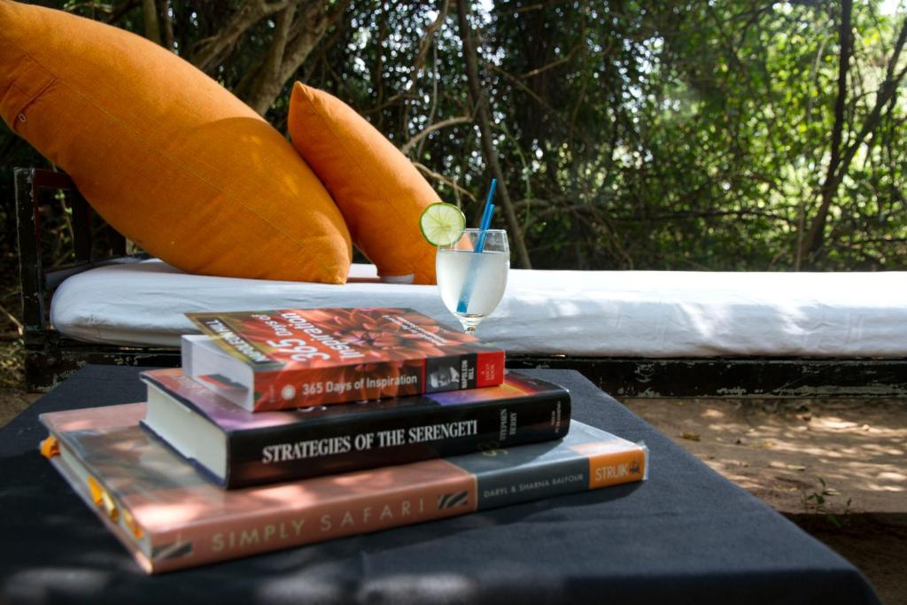 a stack of books sitting on a table with a drink at Mahoora Wilpattu - by Eco Team in Wilpattu
