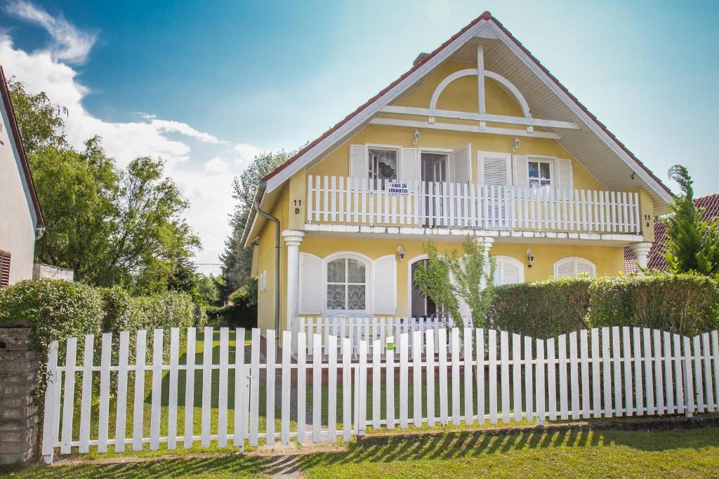 バラトンマーリアフュルドゥーにあるFamilia Nyaraló 47の白いピケの柵の黄色い家