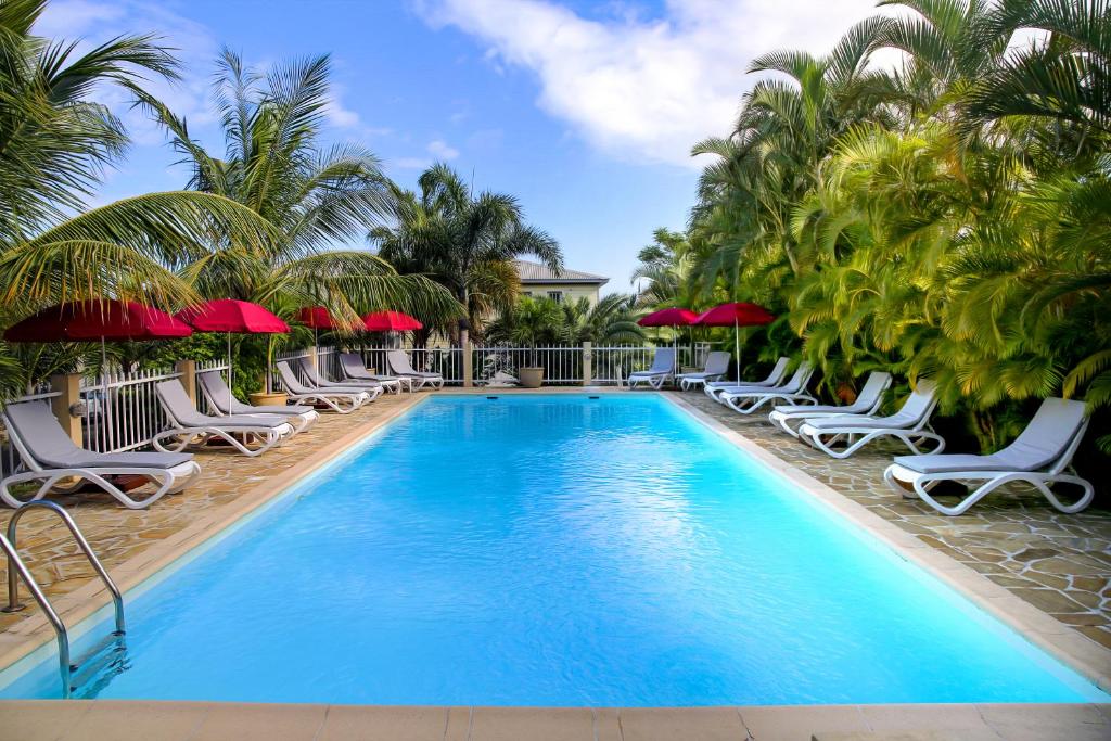 a pool with lounge chairs and palm trees at Résidence Oasis de Terre Rouge in Saint-Pierre