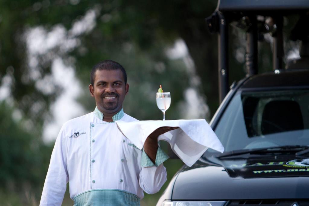 a man holding a candle and a glass of wine at Mahoora Wilpattu - by Eco Team in Wilpattu