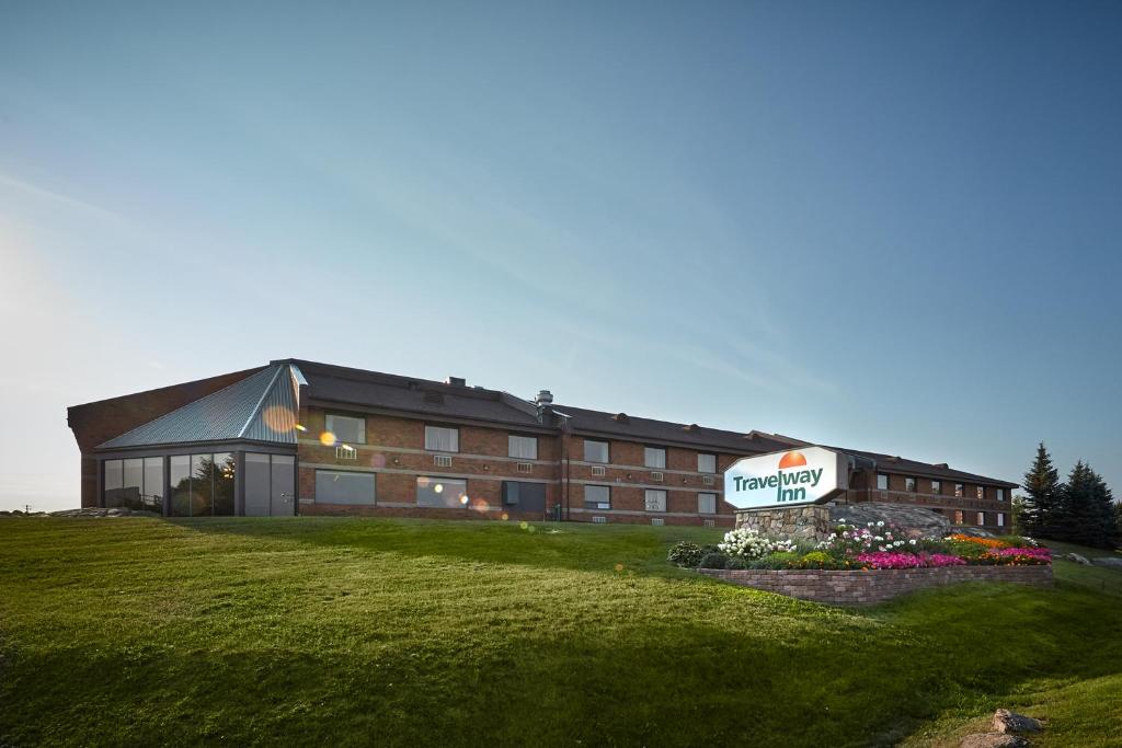 un gran edificio con un cartel delante en Travelway Inn Sudbury, en Sudbury