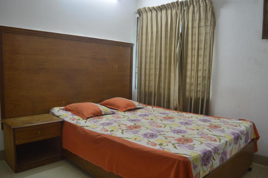 a bedroom with a bed with a wooden headboard and a window at Hyperion Sea View in Cox's Bazar
