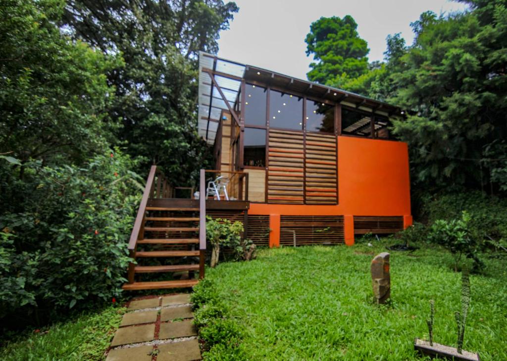 ein Haus mit einer orangefarbenen Fassade und einer Treppe in einem Hof in der Unterkunft Casa Higueron in Monteverde Costa Rica