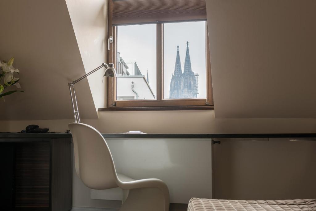 um quarto com uma cadeira e uma janela com um edifício em Hotel Casa Colonia em Colônia