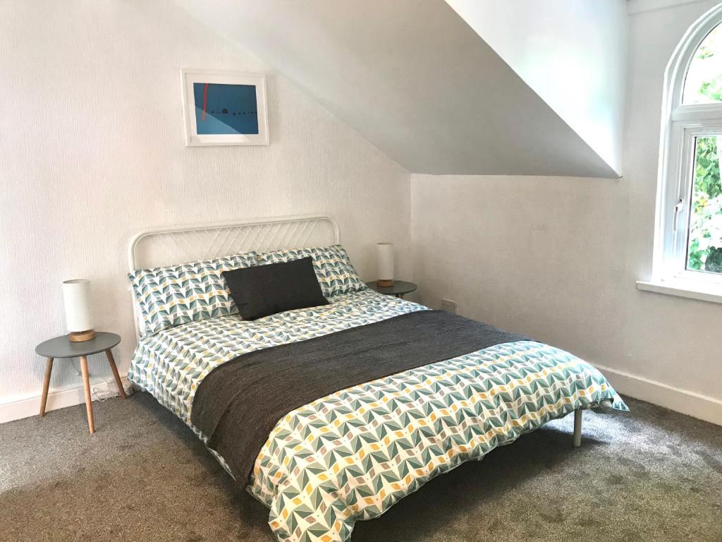 een slaapkamer met een bed, twee tafels en een raam bij Castleton townhouse in Belfast