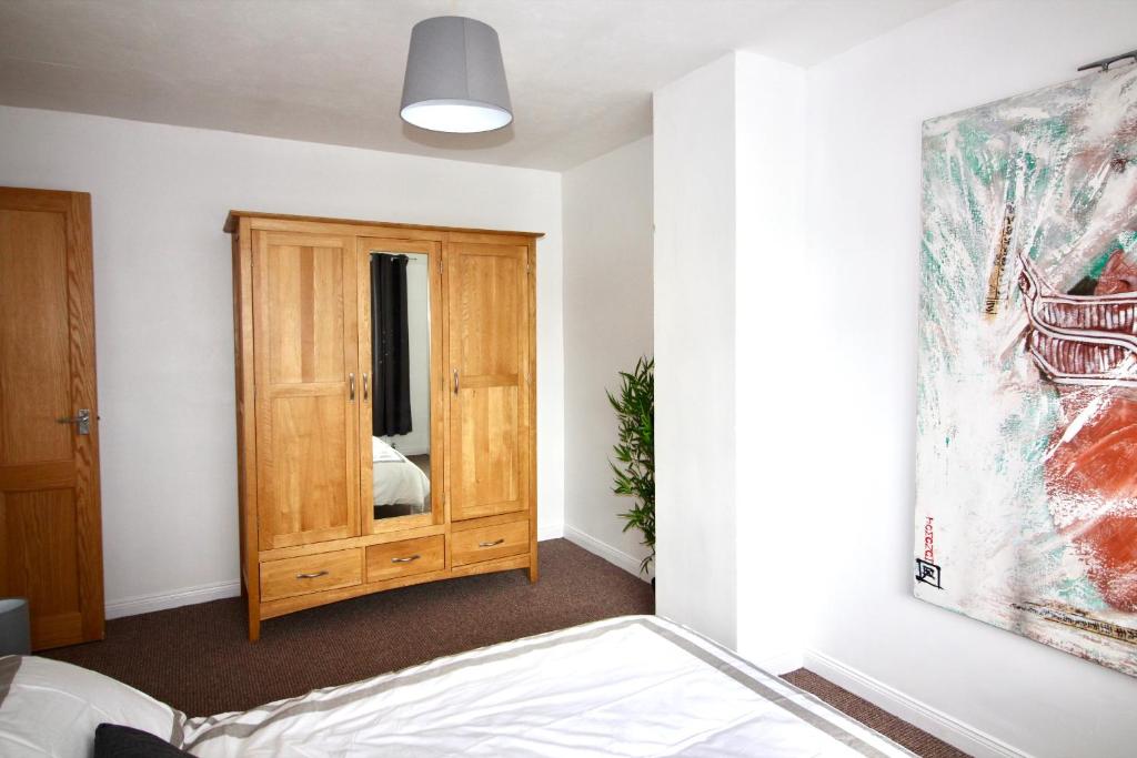 a bedroom with a bed and a wooden cabinet at Carwood House in Newtownabbey