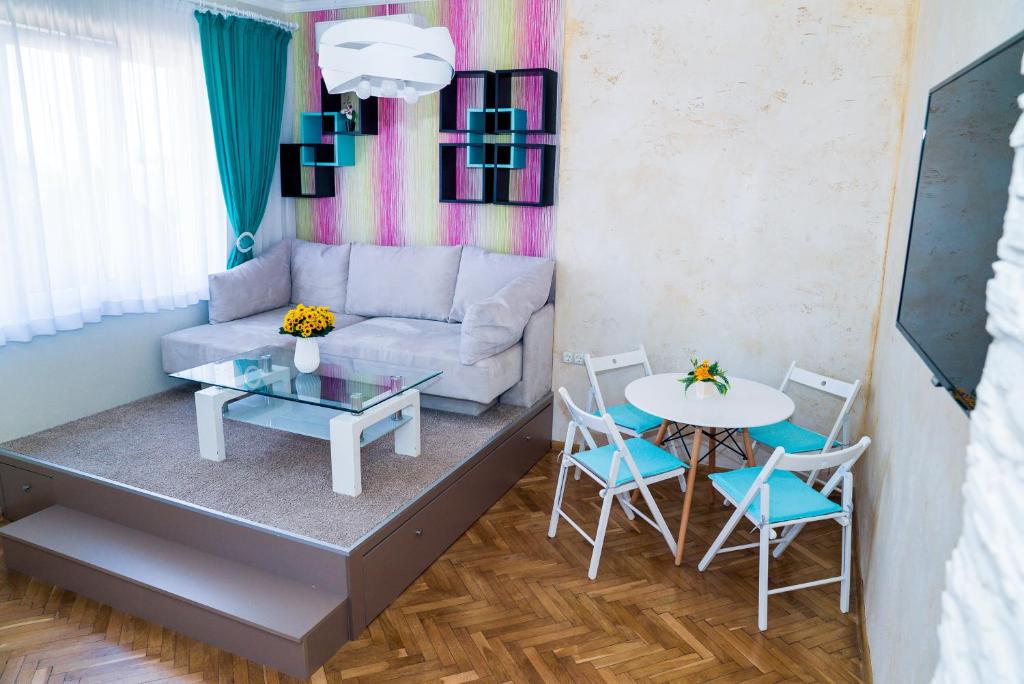 Una sala de estar con un sofá, una mesa y sillas. en Sofia Central Pretty Apartment, en Sofía