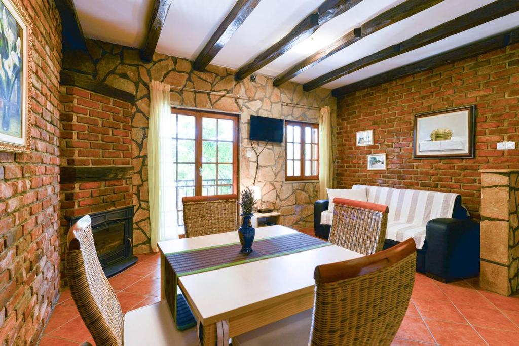 salon ze stołem i ceglaną ścianą w obiekcie Villa Steffany Apartments w mieście Kolan
