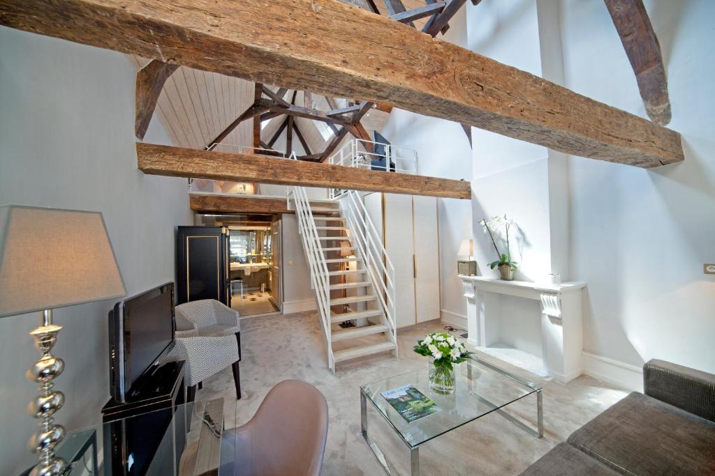 a living room with a staircase in the ceiling at Hotel Le Place d'Armes - Relais & Châteaux in Luxembourg