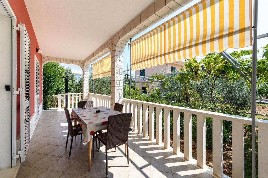 a patio with a table and chairs on a balcony at Holiday home VesnaD-25m from beach in Seget Vranjica