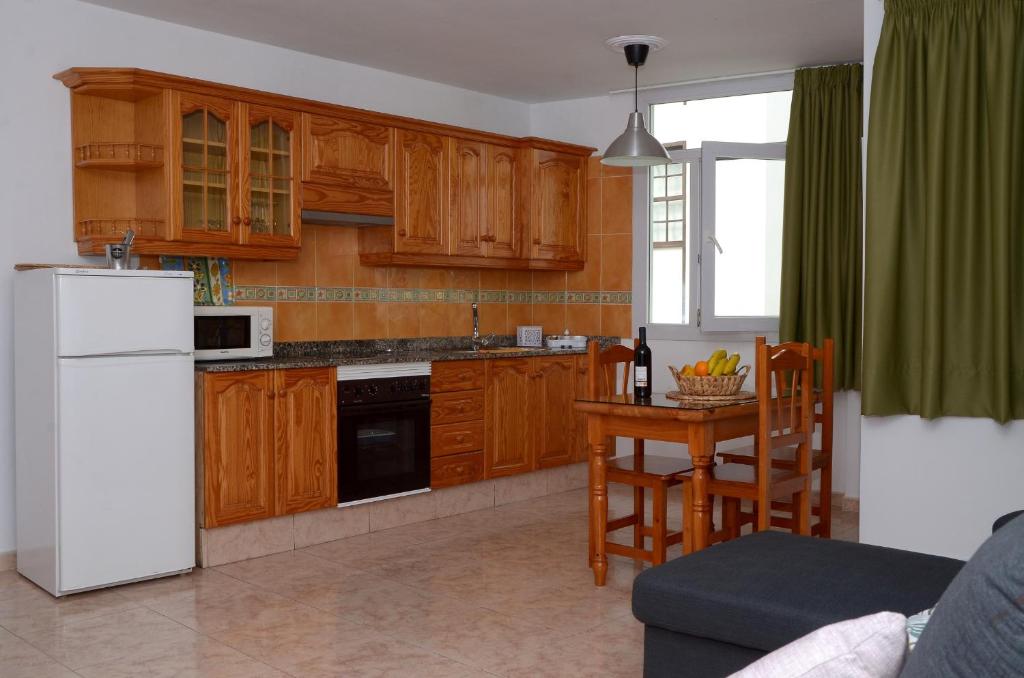 ロス・ジャノス・デ・アリダネにあるApartamento Yerayのキッチン(木製キャビネット、テーブル、白い冷蔵庫付)