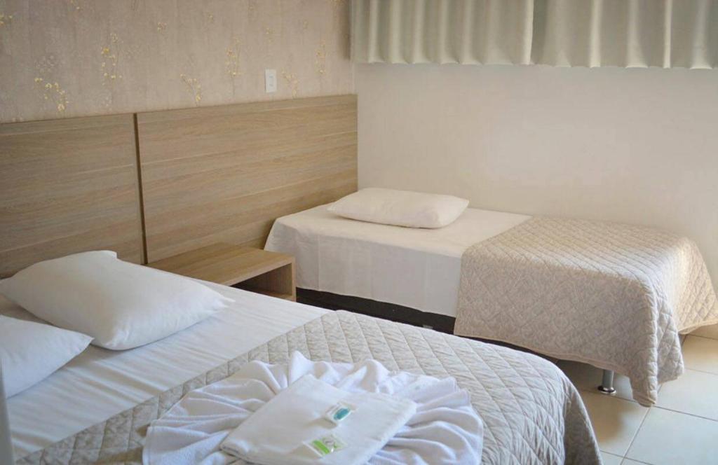 a hotel room with two beds with white sheets at Star Hotel in Chapecó