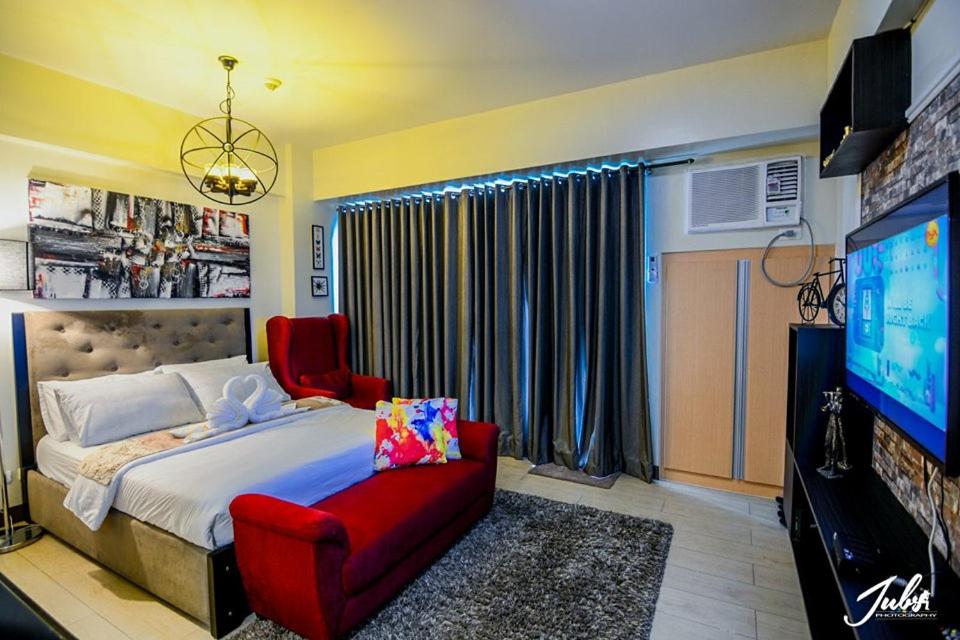 a bedroom with a bed and a tv and a red chair at Norico's Condo in Manila