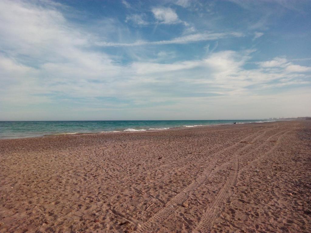 une plage avec des pistes de pneus dans le sable et l'océan dans l'établissement Apartmento playa Almarda. Piscina&Parking, à Almardá