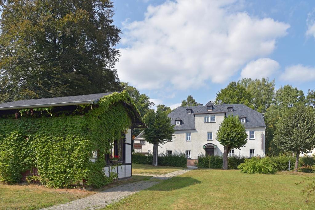 Ein weißes Haus, auf dem Efeu wächst. in der Unterkunft Parkhotel Ebersdorf in Saalburg