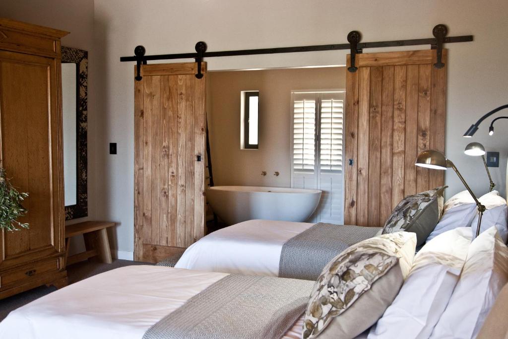 a bedroom with two beds and a bath tub at d'Olyfboom Guest House B & B in Paarl