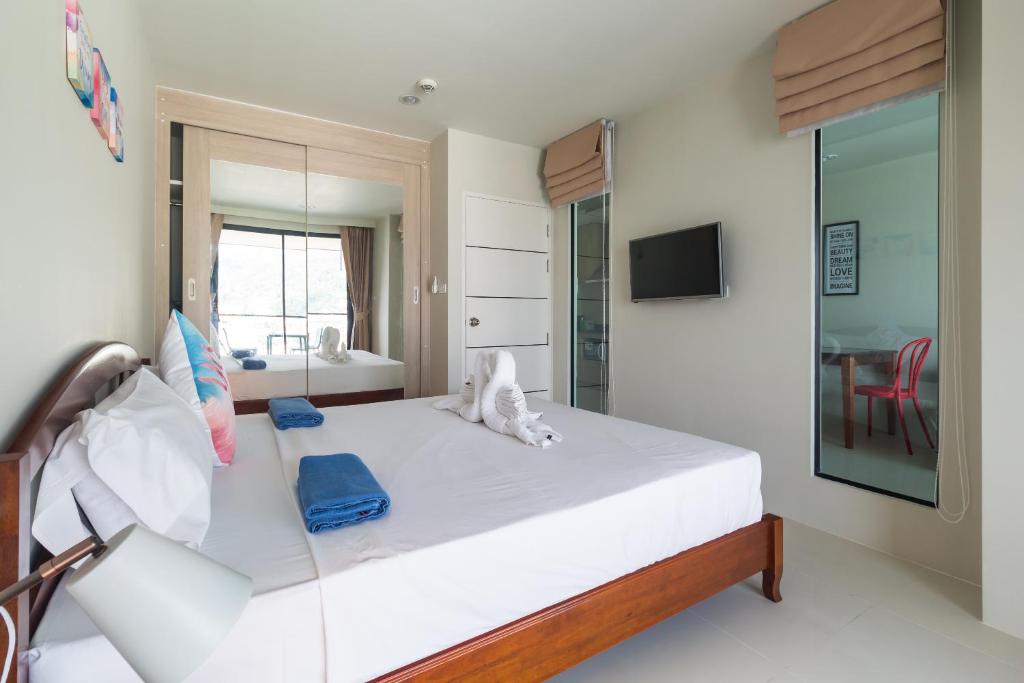 a bedroom with a large white bed with a mirror at Apartments at The Bliss Condo by Lofty in Patong Beach
