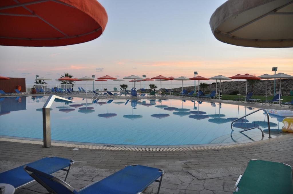 a large swimming pool with chairs and umbrellas at Aktea Beach Village in Ayia Napa