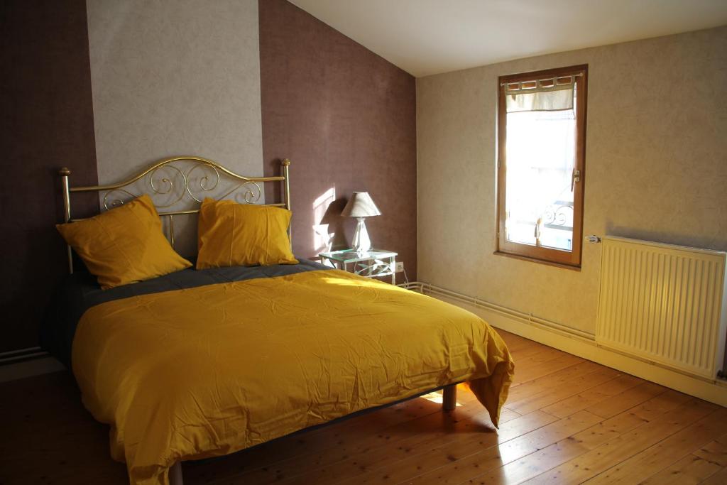a bedroom with a bed with a yellow comforter and a window at Rêve Fontaine in Joinville
