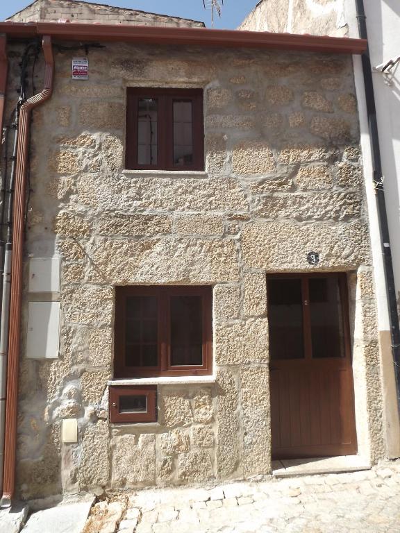 a stone building with three windows and a wooden door at Casa dos Poetas by AL Belmonte in Belmonte