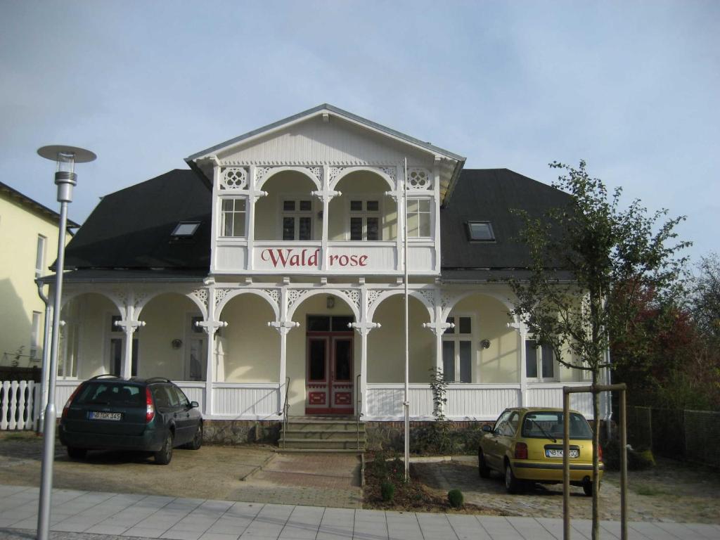 un edificio con un cartel que lee la casa de la pared en Pension Waldrose, en Ostseebad Sellin