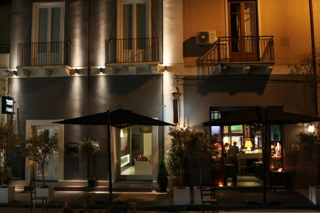 a restaurant with tables and umbrellas in front of a building at Locanda del Bagatto in Milazzo